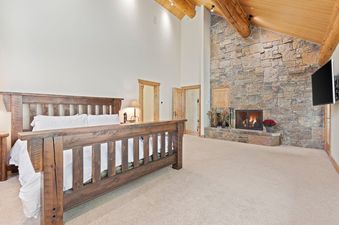 A large bedroom with a king size bed and a fireplace.