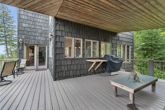 A private deck at Elk Run features a gray composite deck, dark cedar shake siding, and a warm wooden ceiling, with glass doors leading indoors.