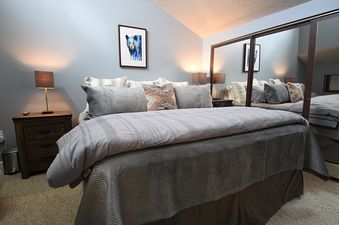A cozy bedroom with a comfortable bed, two nightstands with lamps, and a mirrored closet.