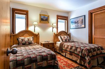 A cozy bedroom in Nez Perce A6 featuring two twin beds with plaid quilts and wooden headboards.