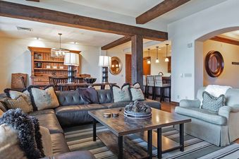 The Silver Strike Deer Valley living room features a spacious leather sectional sofa with decorative pillows and a large wooden coffee table adorned with pinecones.