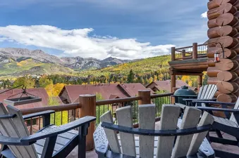 A private balcony at TRISTANT 115 offers stunning views of the surrounding mountains and autumn foliage, with comfortable Adirondack chairs and a BBQ grill.