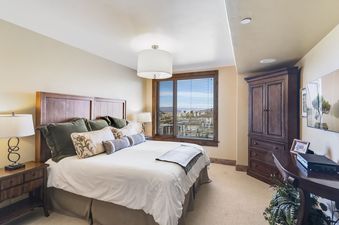 A bedroom with a large bed, a dresser, and a view of the mountains.
