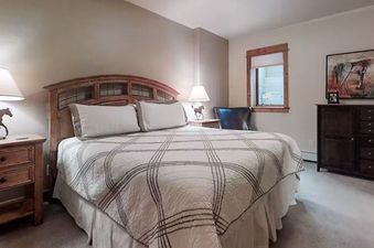 A bedroom in EagleRidge Townhomes 1516 with a bed, dresser, a lamp and artwork.
