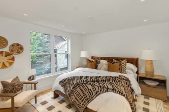 A king bedroom in Mears Station B with a brown tufted headboard, white bedding, gold and black accent pillows, and a black and tan striped throw blanket.