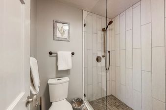 The bathroom in Wildflower Unit 8 features a glass shower stall and a toilet.