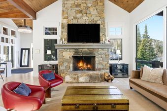 Cozy great room at Snow Dance at The Colony featuring a stone fireplace and red armchairs.