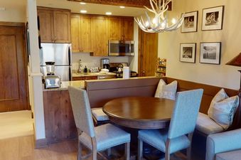 Manor Vail 274 features a kitchen with stainless steel appliances, wood cabinets, and a dining area with a table and chairs.