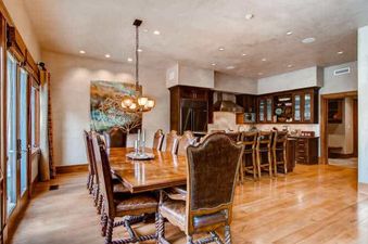 A spacious open-concept dining room with a large wooden table and leather chairs, leading into a gourmet kitchen with dark wood cabinetry and modern appliances.