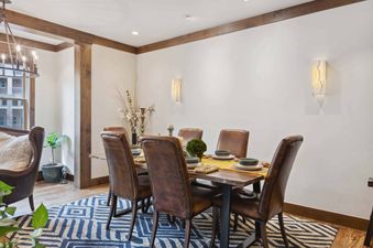 The dining room in Woodrun Place 20 features a large wooden table with leather chairs, and a yellow runner.