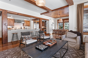 The living room of Grand Lodge Four Bedroom 306 features a large, comfortable couch, two chairs, a coffee table, a rug, and a view of the surrounding area through the windows.