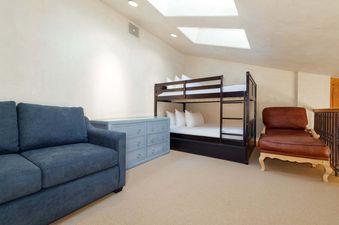 A cozy bunk room in Peaks Penthouse 617 features a comfortable bunk bed, a blue sofa, and a leather lounge chair, perfect for relaxation.
