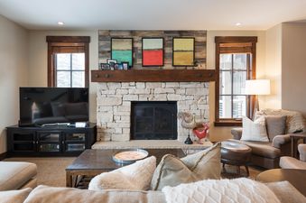 A cozy living room in Silver Star 603 with a stone fireplace, abstract art, a flat-screen TV, and comfortable seating.