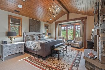 Elegant bedroom in Alpine Sanctuary featuring a king-sized bed and stone fireplace.