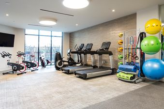 A gym with treadmills, exercise bikes, and exercise balls.