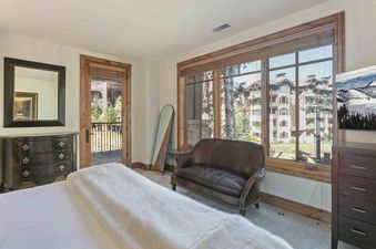 Cozy bedroom at Shooting Star 106 featuring a brown leather couch and a large window with mountain views.