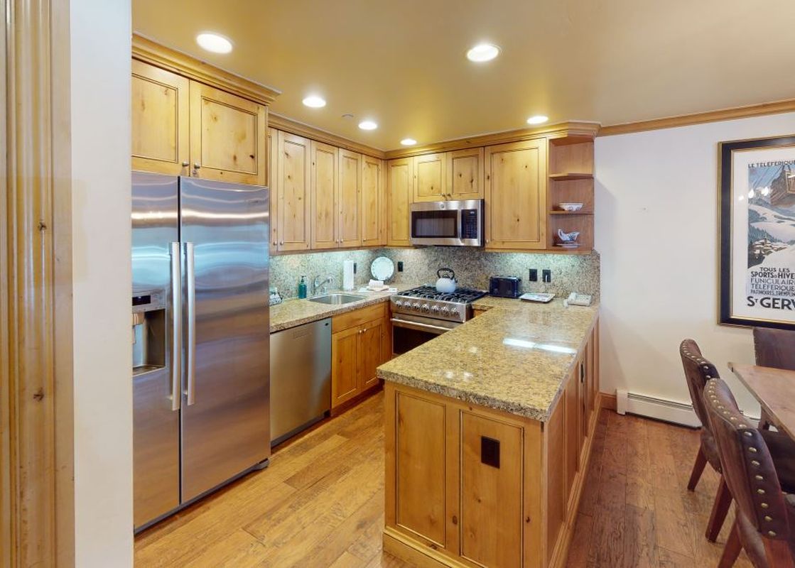 The kitchen at Manor Vail 115 has stainless steel appliances, wooden cabinets, granite countertops, and a breakfast bar.