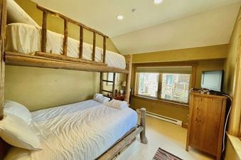 The Arrowhead Village Condominium Platinum 5 Bedroom features a cozy bedroom with rustic wooden bunk beds, providing comfortable lodging.