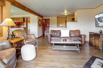 A spacious living room at the Ranch at Steamboat RA201 features comfortable leather seating, a large wall-mounted TV, and a cozy ambiance with wooden accents and warm lighting.