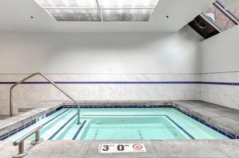 A private hot tub at Copperbottom 311, featuring serene blue water, sparkling white and blue tiled walls, and bright overhead lighting.