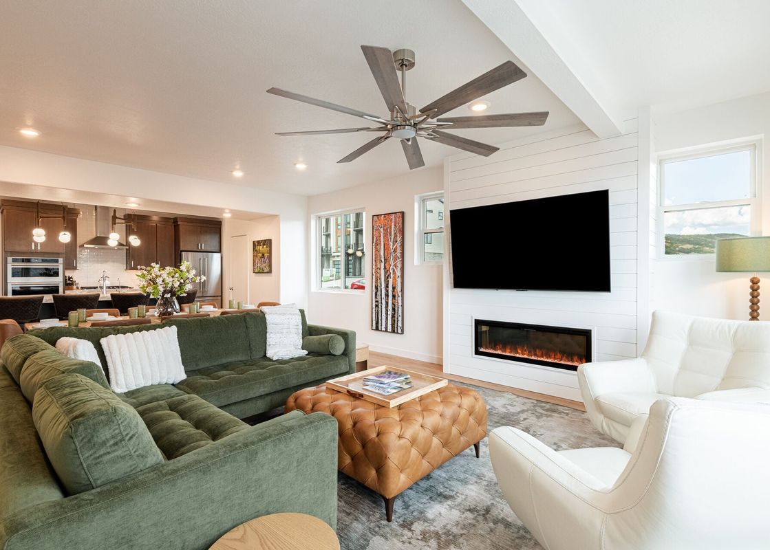 Modern living room at Deer Valley East Above and Beyond with a green sectional, leather ottoman, and electric fireplace.