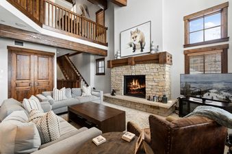 The grand living area of Silver Star 33 features a stone fireplace, a large sectional sofa, and exposed wooden beams, creating a luxurious and inviting lodge-like atmosphere.