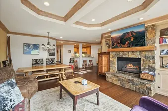 Warm open-plan living area in Centrum 302 with a stone fireplace, flat-screen TV, and wooden dining table.