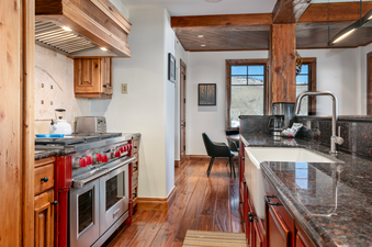 The spacious kitchen of Grand Lodge Three Bedroom 301 features a large, stainless steel stove and oven, granite countertops, and a large farmhouse sink.