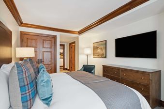 The bedroom in Park Hyatt 4051 features a comfortable bed with plush pillows, a wall-mounted TV, and elegant wooden furniture.