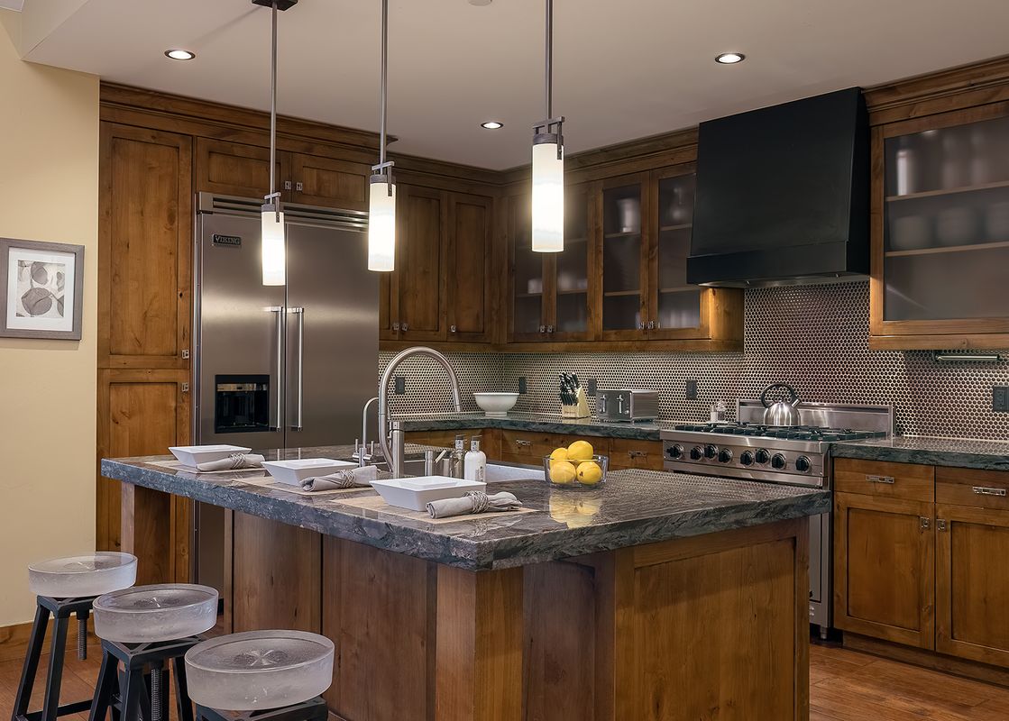 Sophisticated kitchen at Flat Tops Peak Penthouse One Steamboat Place 701 with dark marble countertops and wood cabinetry.