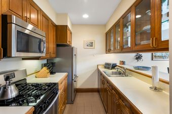 The kitchen has wooden cabinetry, stainless steel appliances, and a gas range.