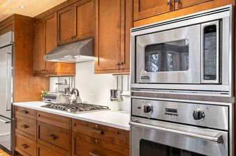 A modern kitchen boasts sleek wooden cabinetry, stainless steel appliances including a Viking microwave and oven, and a white countertop with a gas stovetop.