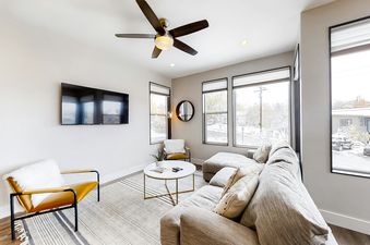 The living area features comfortable seating, a TV, and large windows with outdoor views.