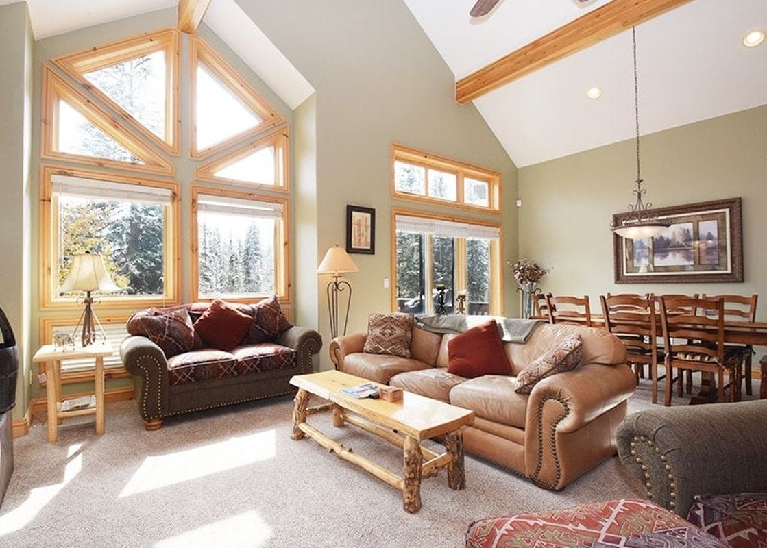 A spacious and inviting living area and dining room within Timberlake 341, featuring comfortable sofas, a rustic coffee table, a dining set, and large windows with outdoor views.