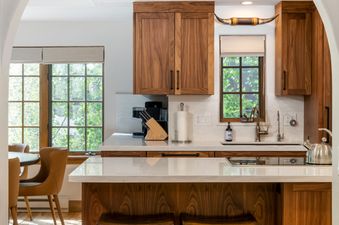 A modern kitchen with rich wooden cabinetry and light countertops features a spacious island with stools, creating a sophisticated and functional culinary space in the Bridge Street Lodge 3 Bedroom Diamond Unit 309.