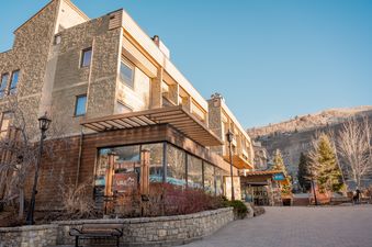The exterior of Vail 21 307 under a blue sky, showcasing its unique architecture and surrounding natural landscape.