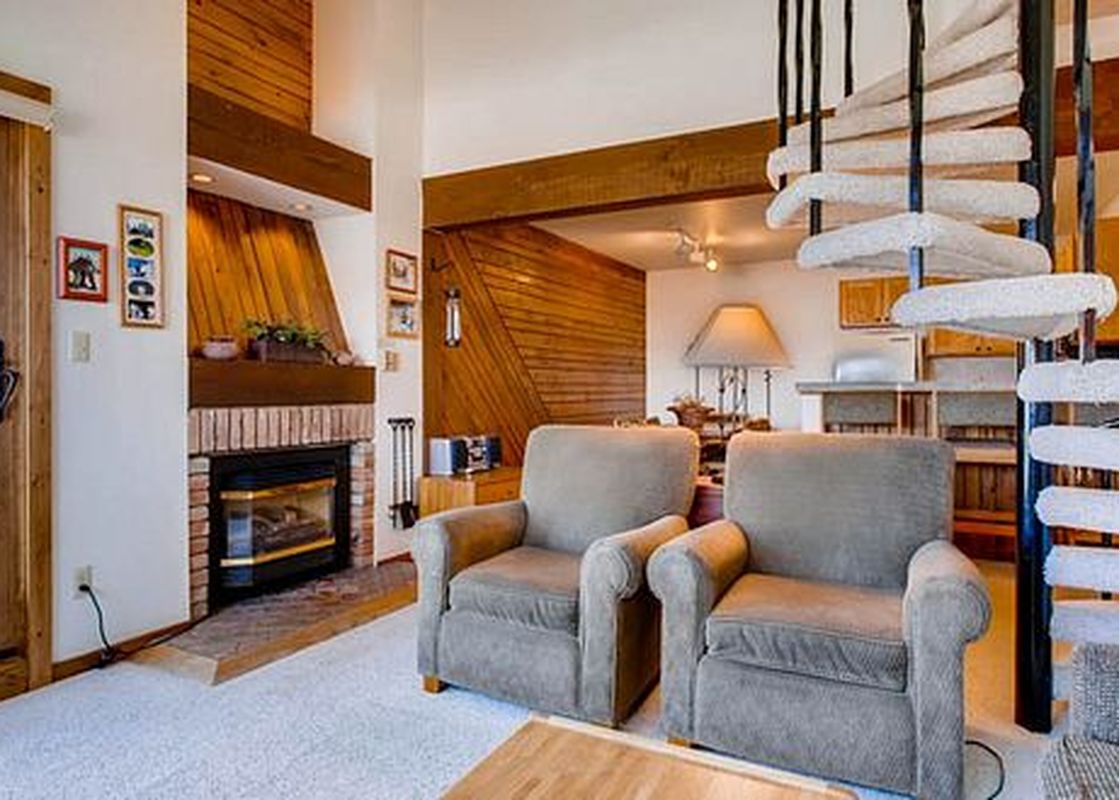 The living area of Buttes 2 Peak 517 features a fireplace, two armchairs, a spiral staircase, and a glass door leading to a balcony.