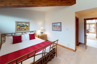 The master bedroom at Manor Vail 348 is spacious and features a comfortable king-size bed, wooden furniture, artwork, and natural light.