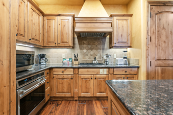 The kitchen in Grand Lodge Studio 205 is well-equipped with stainless steel appliances including a microwave, oven, and stovetop. It also has wood cabinets and granite countertops.