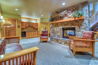 A spacious lodge lounge area with a stone fireplace and a comfortable leather couch and chairs