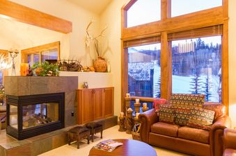 The living room of Terraces 602 features a stone fireplace, large windows, and comfortable leather seating.