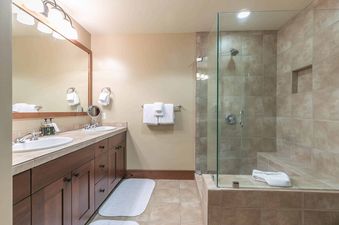 A modern bathroom with a large walk-in shower, double vanity, and white towels.