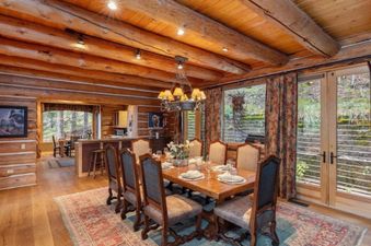 The spacious dining room at 116 Hang Glider Dr features a large wooden table set for a formal meal, surrounded by elegant chairs and bathed in warm, natural light.