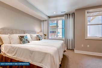 A welcoming guest bedroom at Rio Grande 203 204 featuring a king-sized bed with white bedding and blue accent pillows, a large window, and soft lighting.