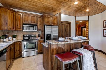 The kitchen features wood cabinets, stainless steel appliances, and an island with seating.