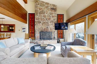 A cozy living room in Timber Ridge 1 with a large stone fireplace, comfortable sofas, and rustic wood accents.