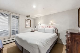A cozy, classically decorated bedroom at Stonebridge at Village Center with a king-size bed and patio doors.