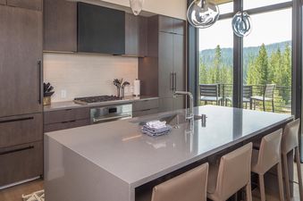 The kitchen in Moonlight Basin 202 Lakelodge features stainless steel appliances, a large island with bar seating, and a view of the mountains.