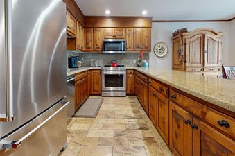 The kitchen in the All Seasons 3 Bedroom Platinum Unit B4 features stainless steel appliances and wood cabinetry.