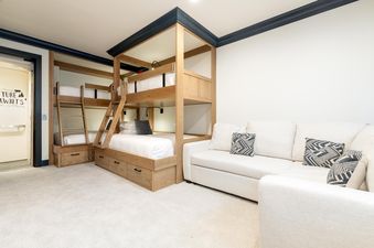 Stone Creek Chalet at The Aspens features a charming bedroom with custom-built bunk beds and a cozy seating area.